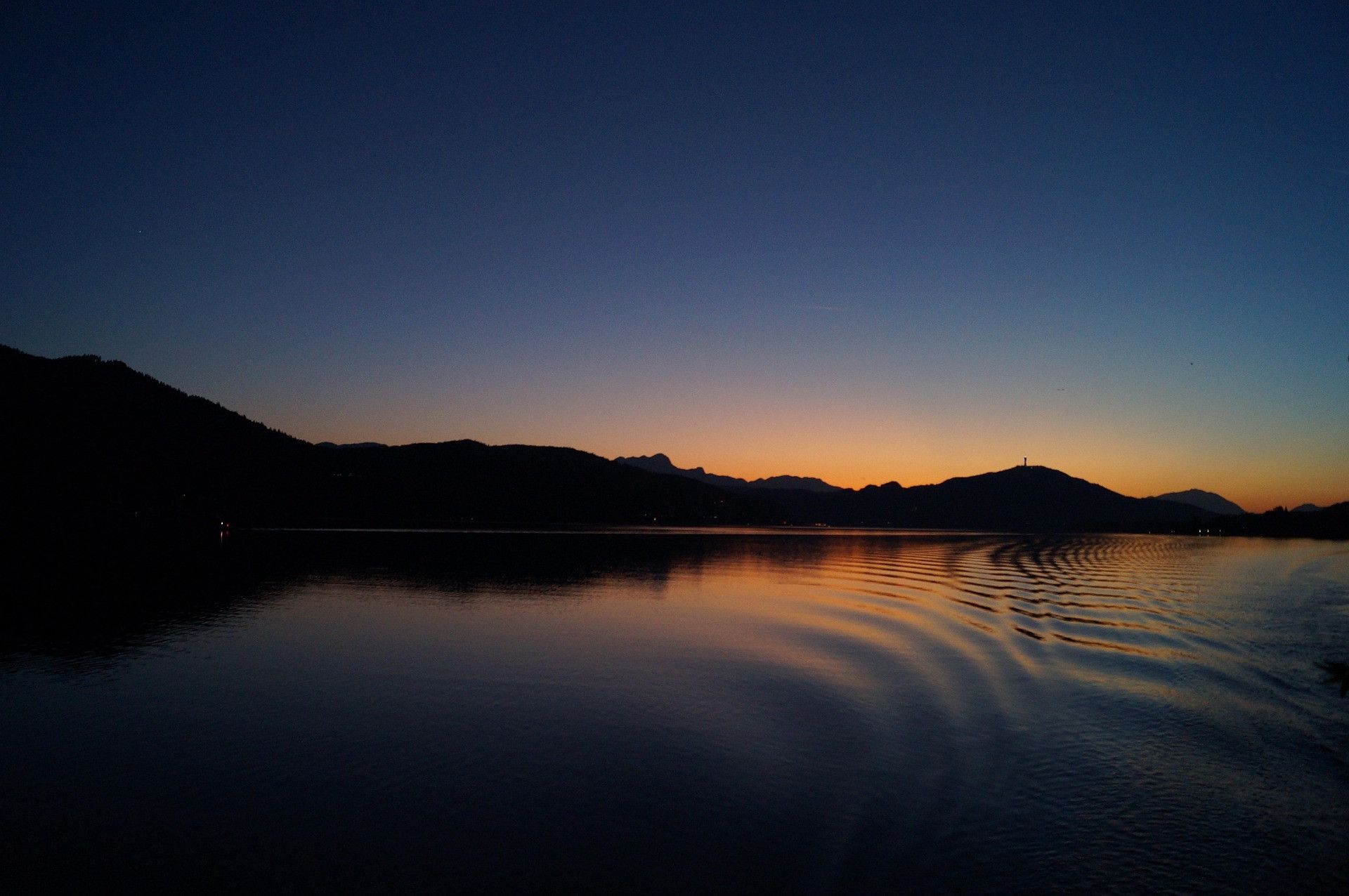 Un lago tranquillo al crepuscolo, con montagne sullo sfondo.