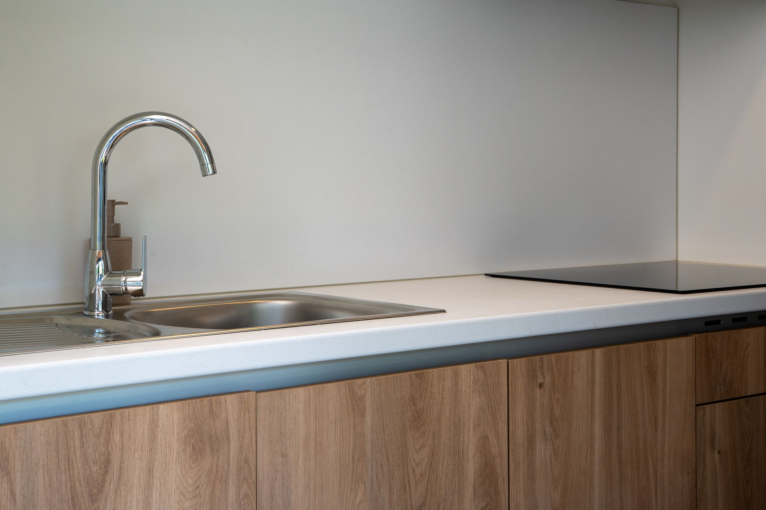 A modern kitchen with a stainless steel sink, a built-in dishwasher, and wooden cabinetry.