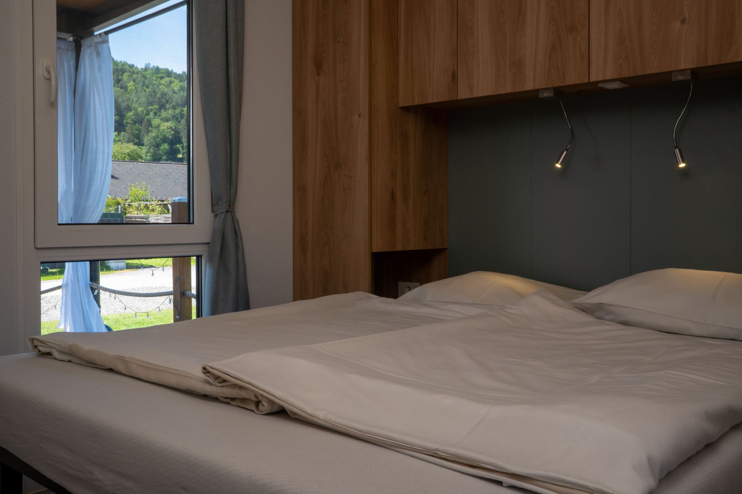 Ein Schlafzimmer mit einem Bett, einem Holzkopfende und einem Fenster mit Vorhängen.
