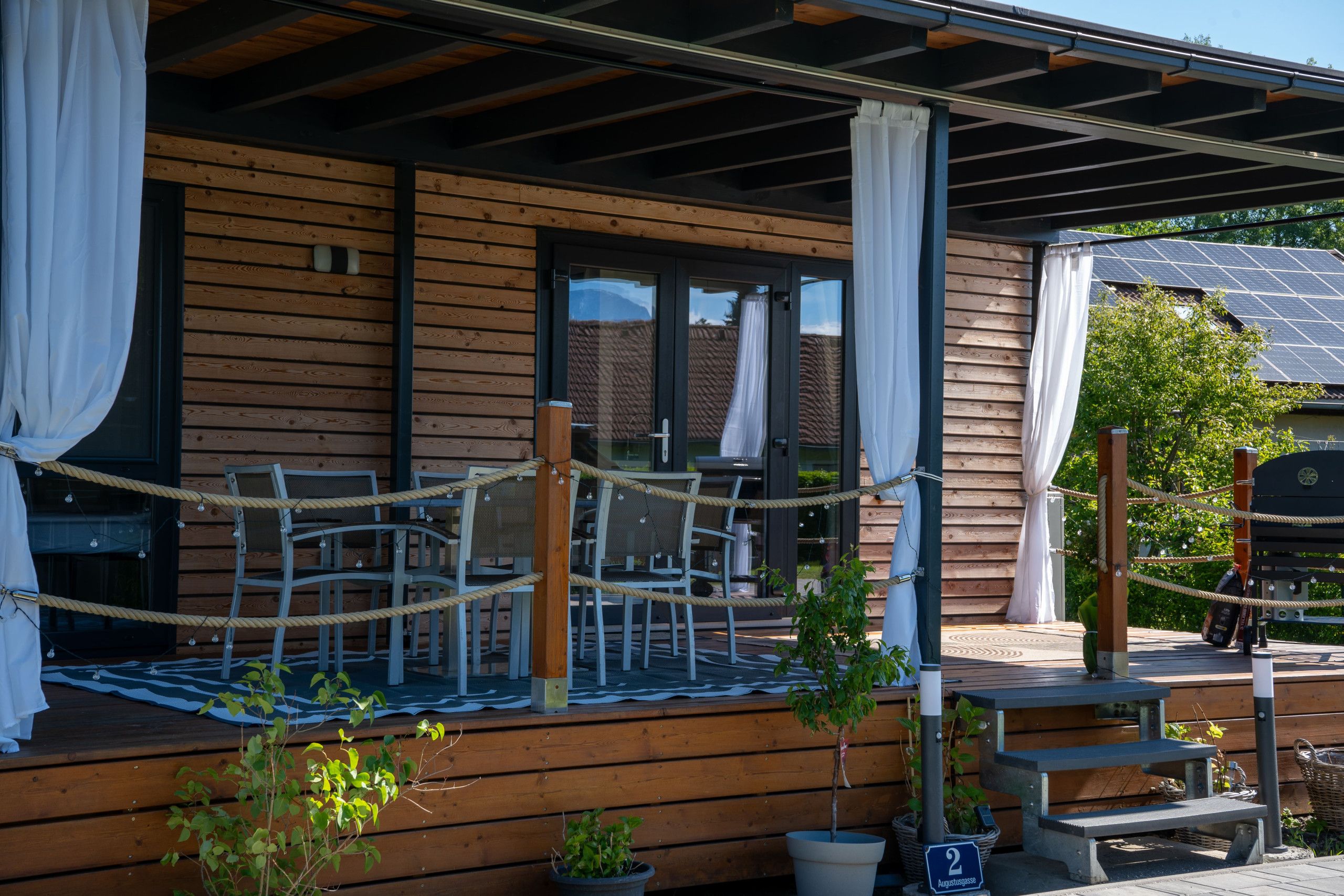 A wooden cabin with a covered porch, outdoor seating, and potted plants.