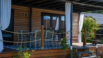 A wooden cabin with a covered porch, outdoor seating, and potted plants.