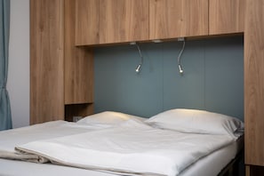 A bed with a wooden headboard and a grey wall behind it. - Sonnendeck Tiny House Klagenfurt by WÖRTHWHILE (Klagenfurt am Wörthersee)