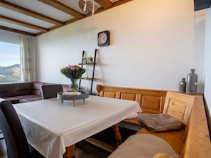 Una habitación acogedora con un banco de madera, una mesa redonda con mantel blanco y un reloj en la pared.