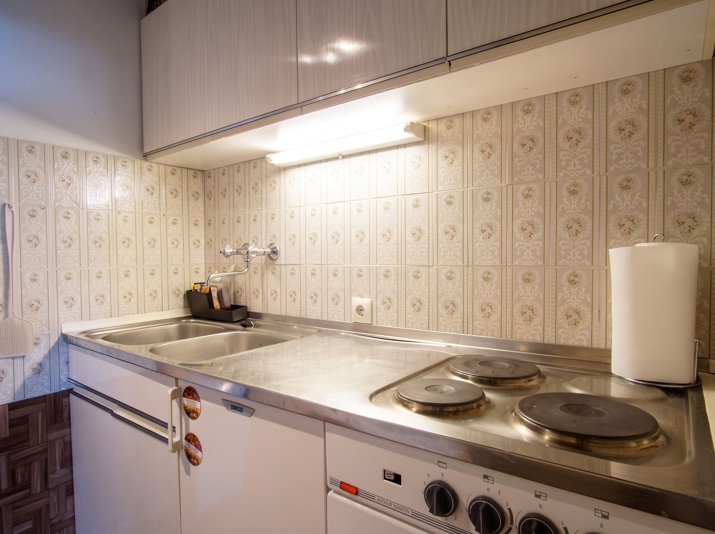 Una cocina con un lavamanos doble, una estufa con cuatro hornillas y un grifo de pared.