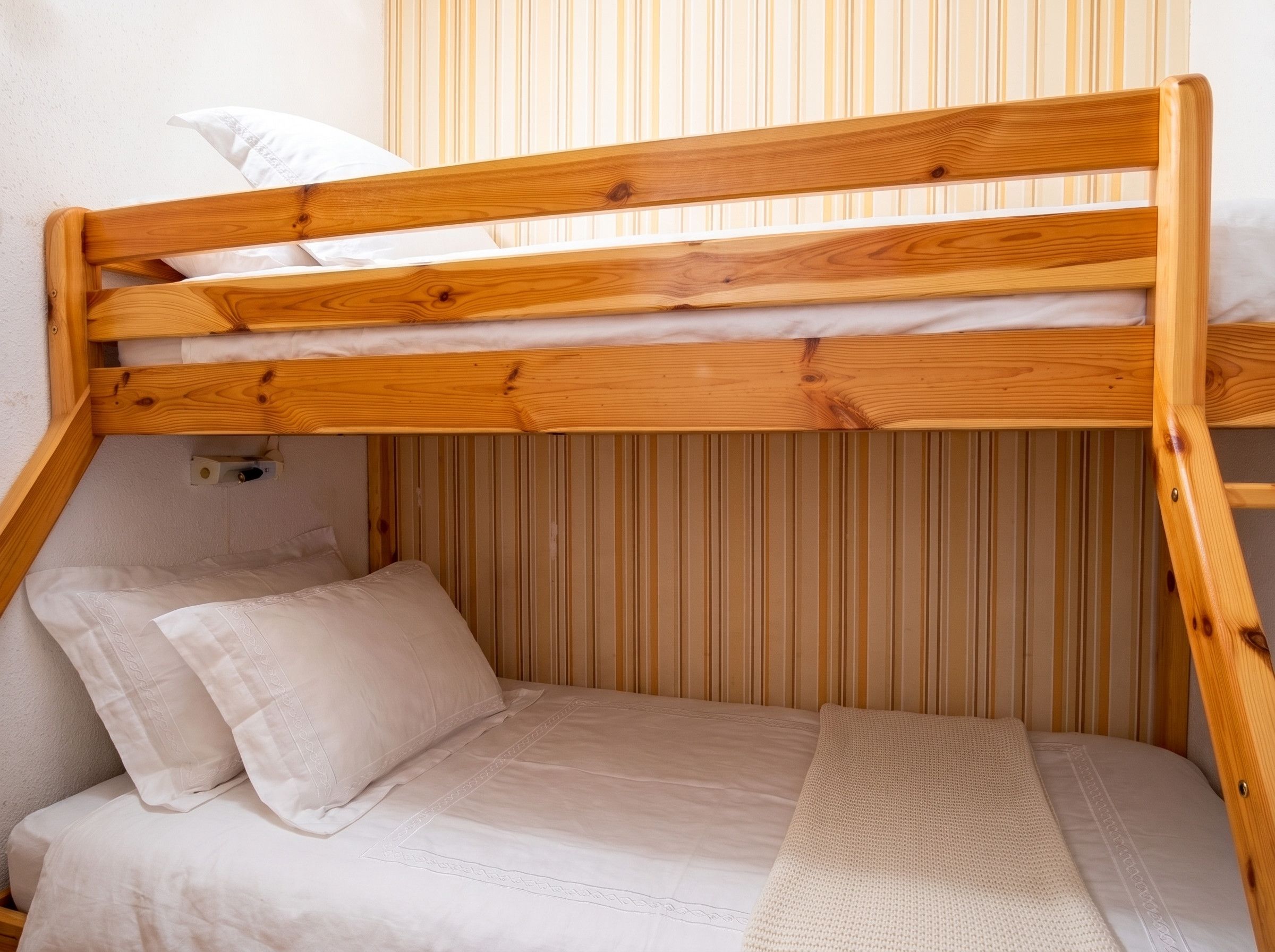 Un letto a castello con struttura in legno e biancheria bianca.