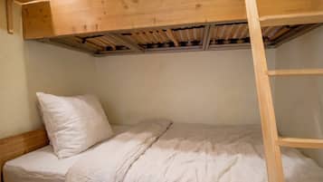 A bunk bed with a wooden frame, a single mattress, and a pillow.