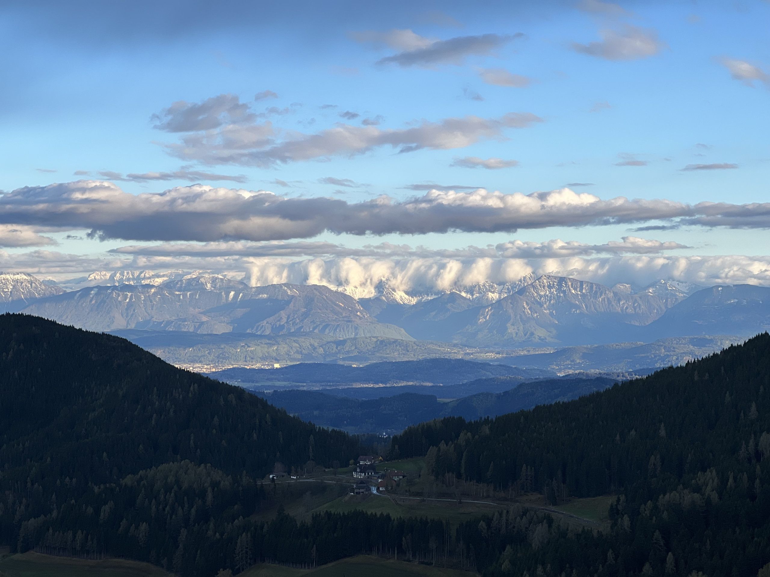 Paesaggio montuoso con una valle, un piccolo insediamento e cielo sereno.