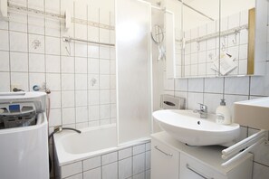 Un baño moderno con bañera, lavamanos y espejo.