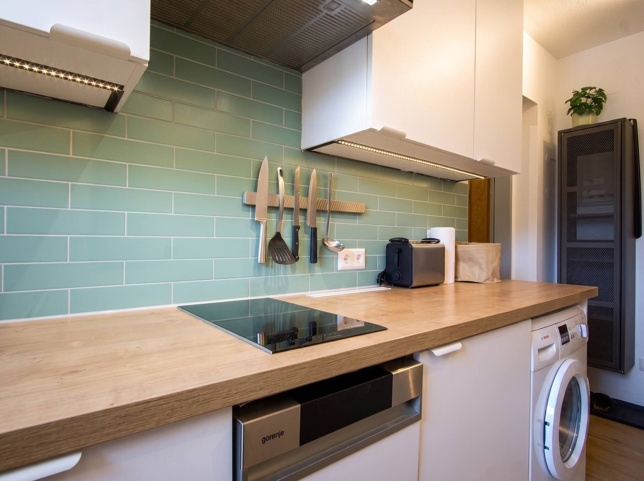 Een moderne keuken met een inbouwvaatwasser, een wasmachine en een aanrecht met een geïntegreerde inductiekookplaat.