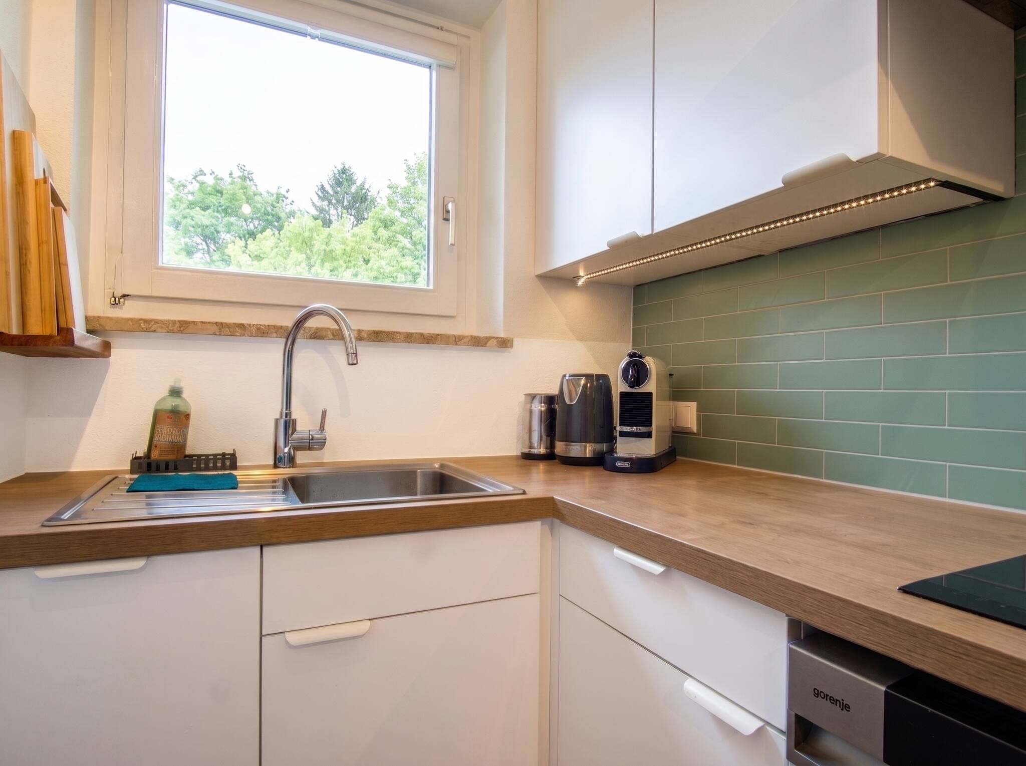 A modern kitchen with a window, stainless steel sink, and a coffee maker.