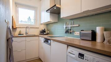 A modern kitchen with a dishwasher, a Bosch washing machine, and a window providing natural light.