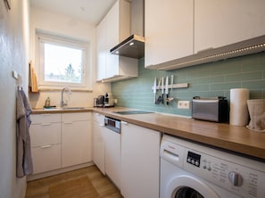 Een moderne keuken met een vaatwasser, een Bosch wasmachine en een raam dat voor natuurlijk licht zorgt.