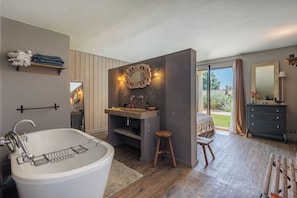 Et moderne badeværelse med et fristående badekar, et toiletbord med spejl og et stort vindue med udsigt til det fri.