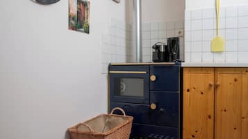 Ett litet kök med en spis, en kaffebryggare och en gul slickepott på bänkskivan.