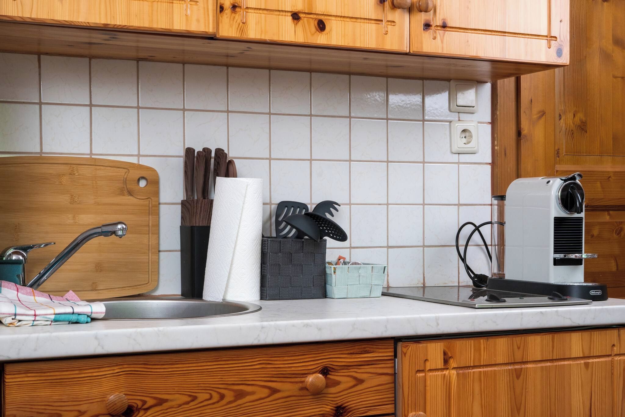 A kitchen with wooden cabinets, a sink, a cutting board, a paper towel holder, and a portable heater.