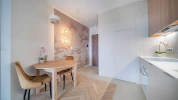 Uma cozinha moderna com piso em padrão herringbone, armários de madeira e área de jantar com mesa e cadeiras redondas.