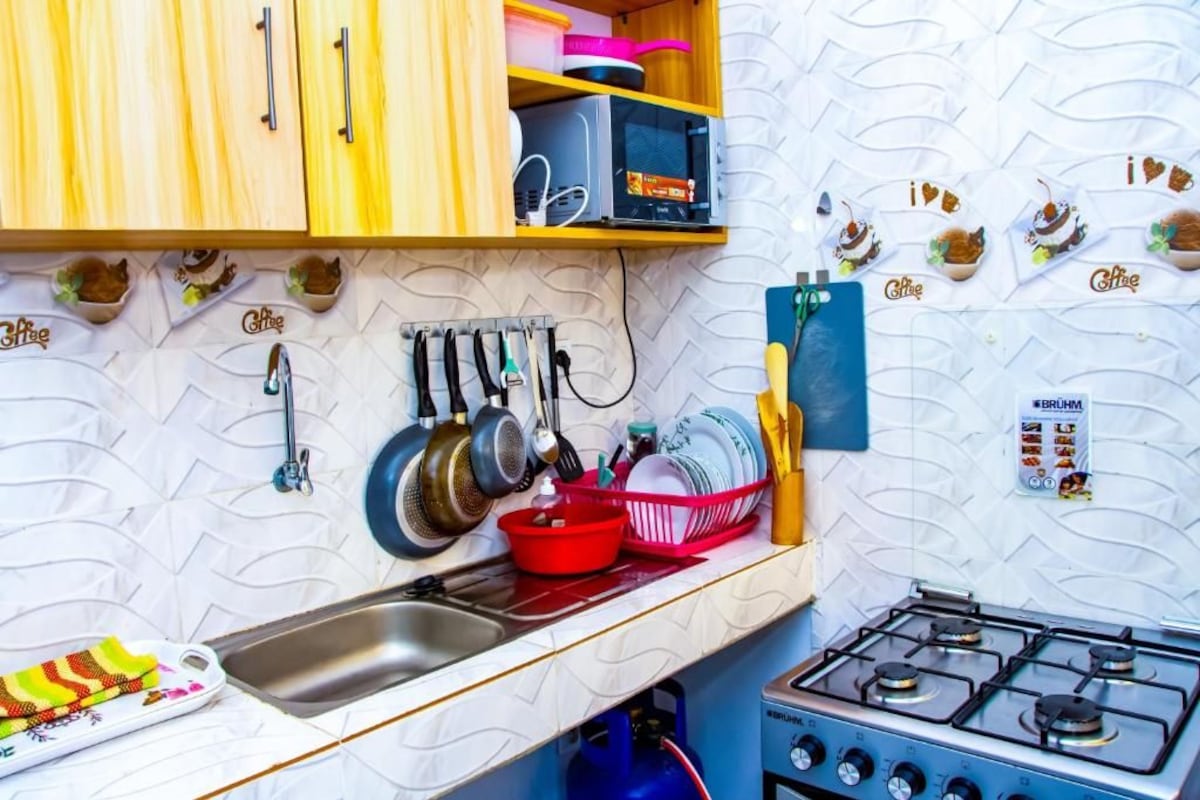A kitchen with wooden cabinets, a gas stove, hanging pots, and a dish rack.