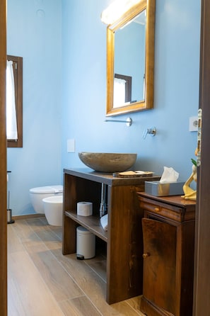 A bathroom with a wooden vanity, a large mirror, a bowl sink, and a toilet. - Rustic Home | Villa with a Garden on the Lake (Ispra)