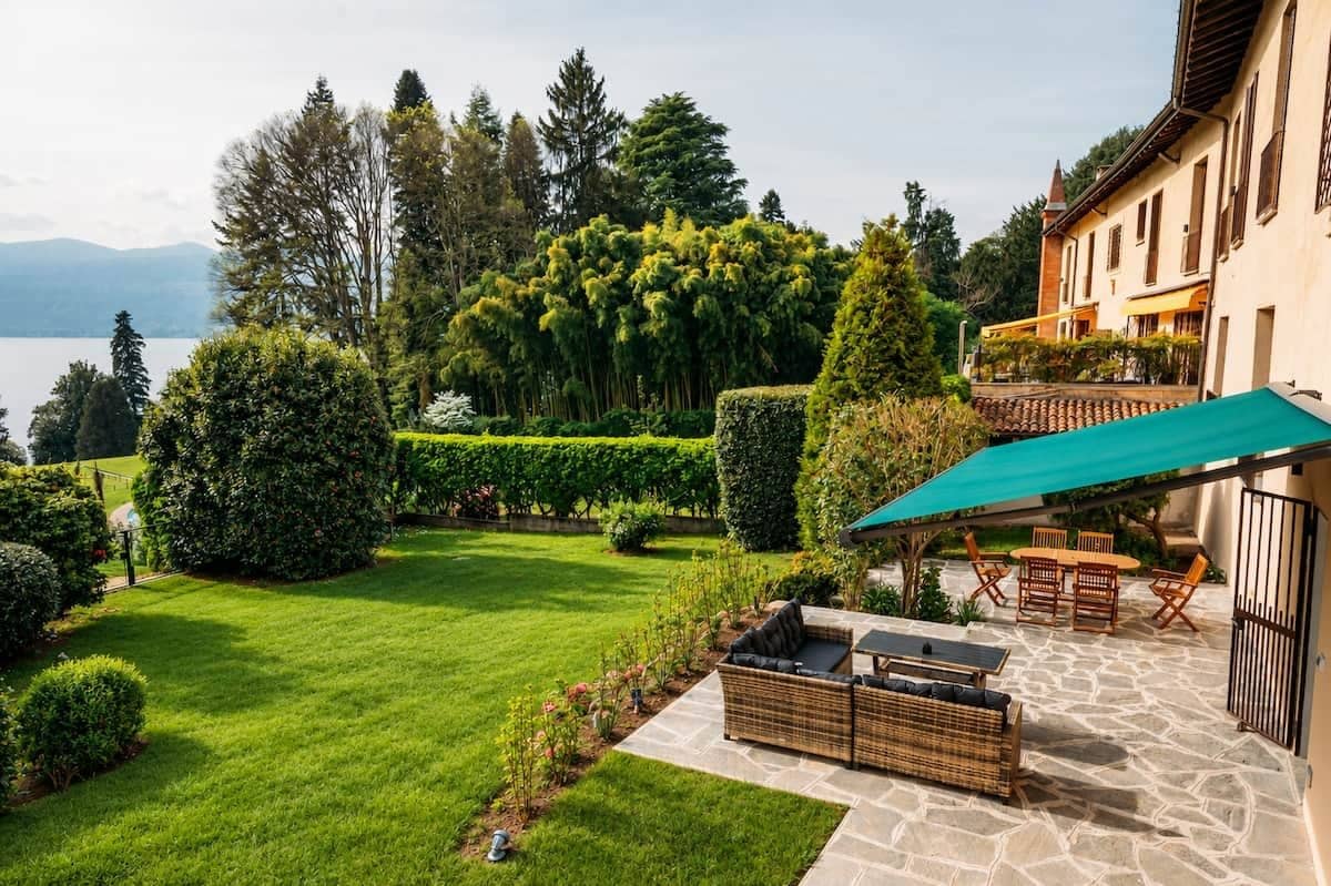 A well-maintained garden with a patio area, outdoor furniture, and a view of a lake and mountains.