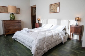 A neatly made bed with a white duvet, a wooden dresser with drawers, two bedside tables with lamps, and a framed picture on the wall. - Rustic Home | Villa with a Garden on the Lake (Ispra)