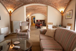 A cozy living room with a brick ceiling, striped sofas, a glass coffee table, and a fireplace. - Rustic Home | Villa with a Garden on the Lake (Ispra)
