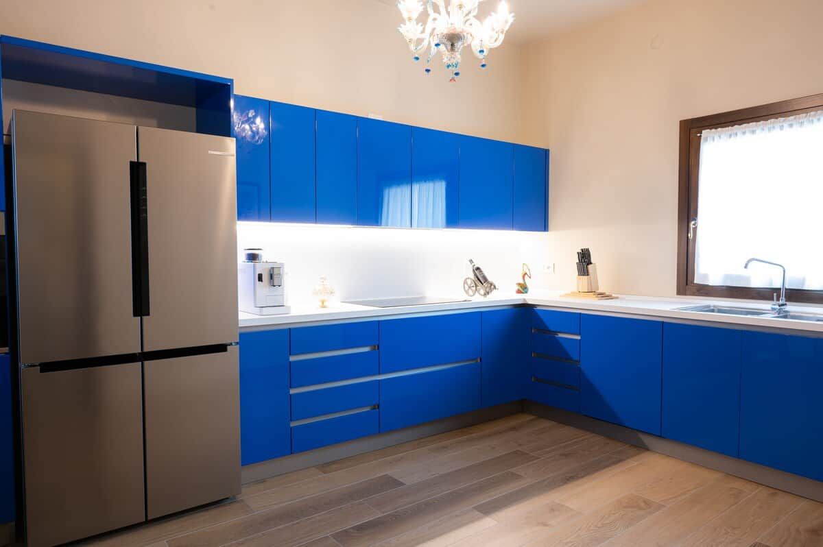 Eine moderne Küche mit blauen Schränken, einem Edelstahlkühlschrank und einem Fenster mit Vorhang.