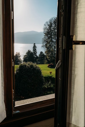 A view through a window with a door frame, overlooking a lake, trees, and a grassy area.