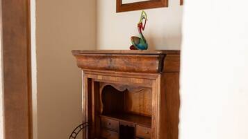Un escritorio de madera con cajones y estante, ubicado en una habitación con pared blanca y un cuadro enmarcado encima.