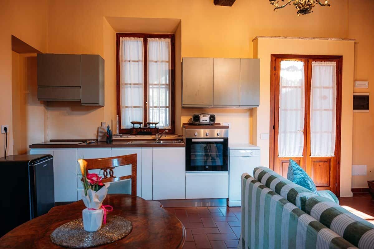 A compact kitchen with a dining area, a sofa, and a window with curtains.
