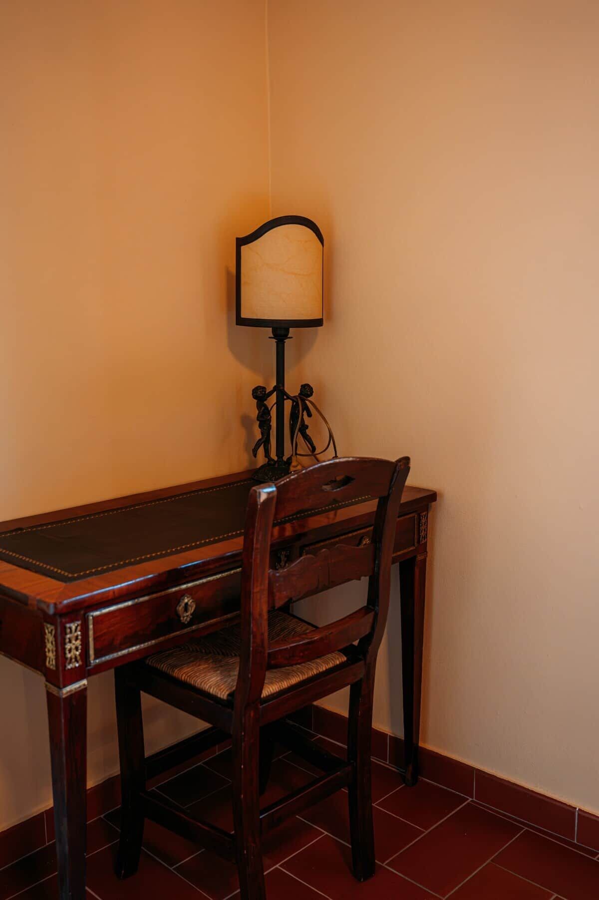 Una scrivania in legno con una sedia, una lampada e un elemento decorativo al muro.