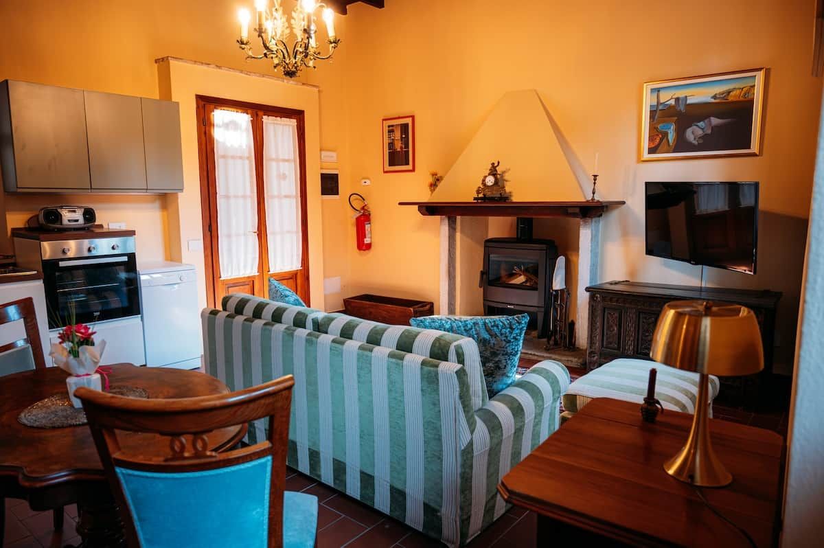 Un salon confortable avec un canapé, une table à manger et des chaises, une cheminée et un téléviseur.