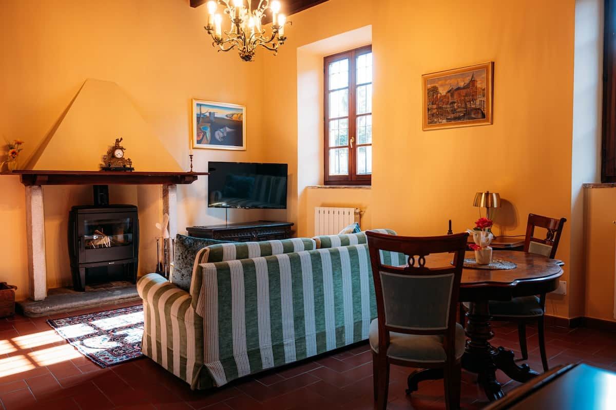 Un salon chaleureux avec une cheminée, un canapé, un téléviseur et un coin repas comprenant des chaises et une table.