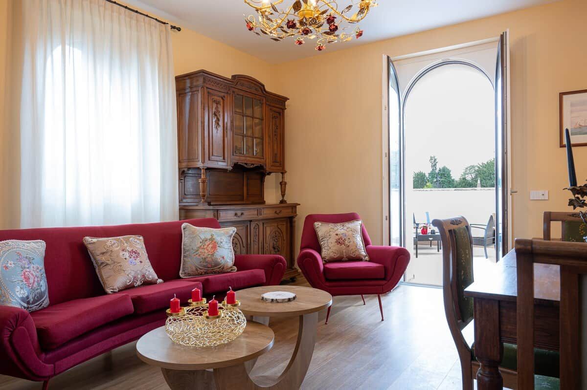 Un salon avec un canapé rouge, un meuble en bois et une table à manger avec des chaises.