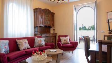 Un salon avec un canapé rouge, un meuble en bois et une table à manger avec des chaises.