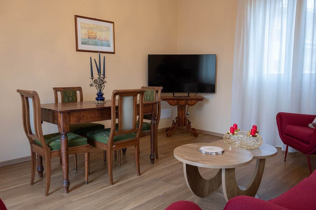 Un salon avec une table à manger en bois, des chaises, un téléviseur et un fauteuil rouge.