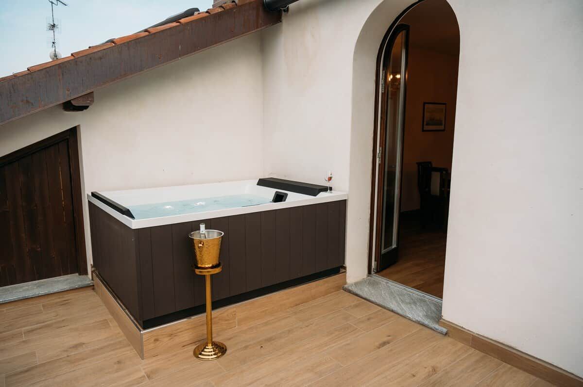 Un espace bien-être comprenant un jacuzzi, un seau doré et un plancher en bois.