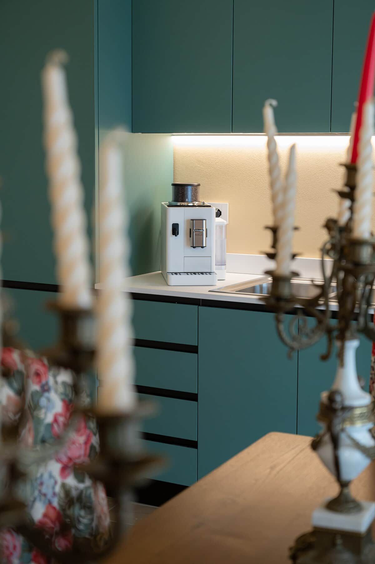 Een keuken met een koffieapparaat, een witte kast en een bloemstuk.