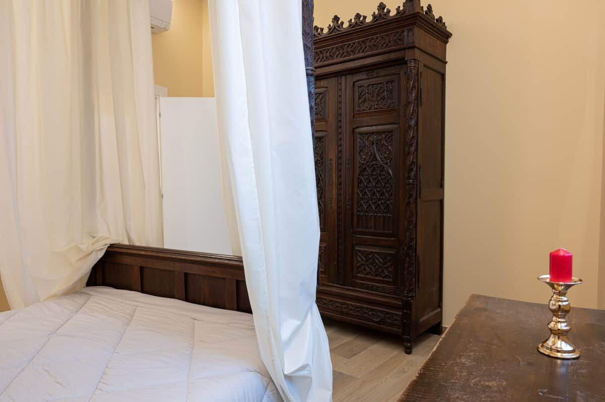 Une chambre à coucher avec un lit, une armoire en bois et une table sur laquelle est posée une bougie.