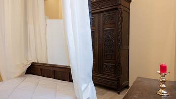 Une chambre à coucher avec un lit, une armoire en bois et une table sur laquelle est posée une bougie.