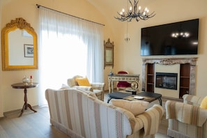 Sala de estar com lareira, um espelho grande e um candelabro.