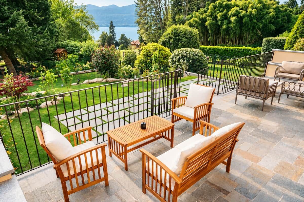 Een terras met uitzicht op een aangelegde tuin en een meer.