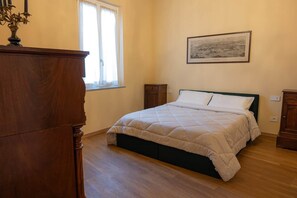 Una camera da letto con un letto, una cassettiera, una finestra e un quadro appeso al muro.