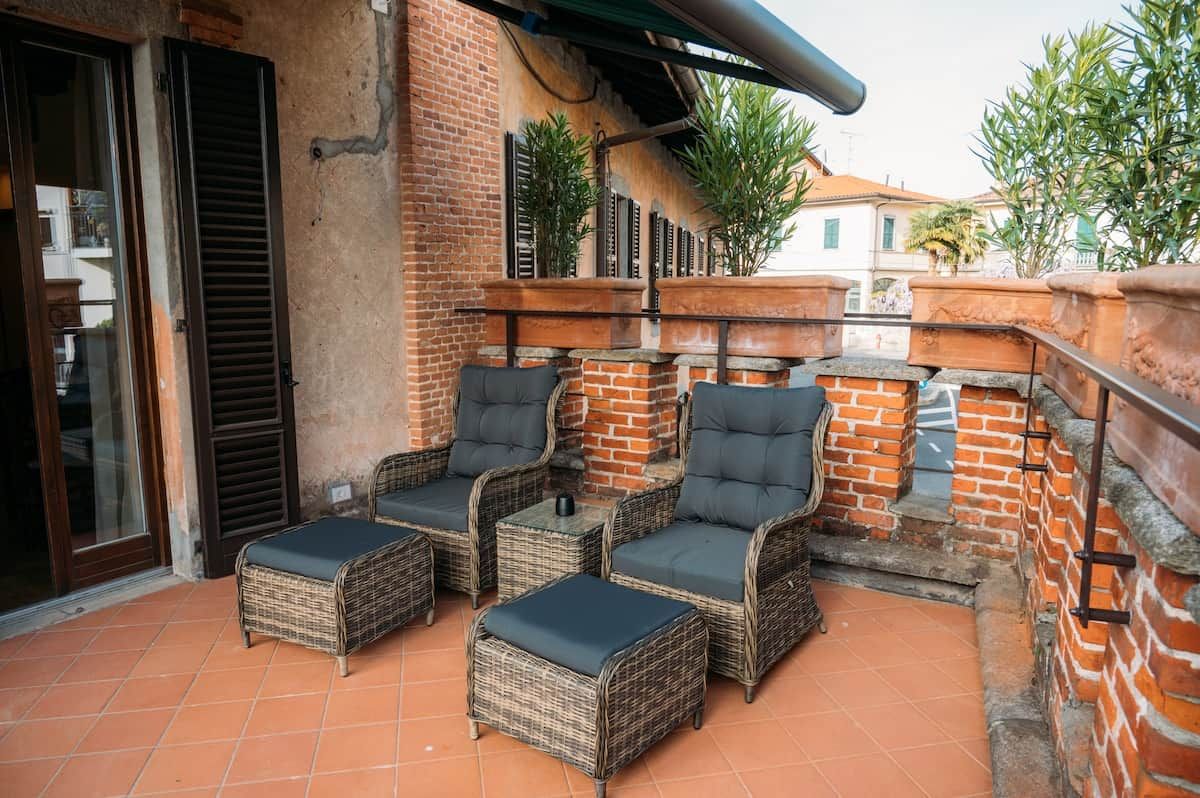 Een terras met wicker meubels en een bakstenen muur.