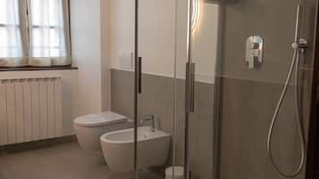 Et moderne badeværelse med en bruseniche bag glas, toilet og bidet.