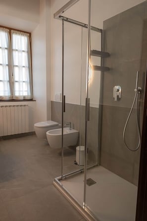 Et moderne badeværelse med en bruseniche bag glas, toilet og bidet.