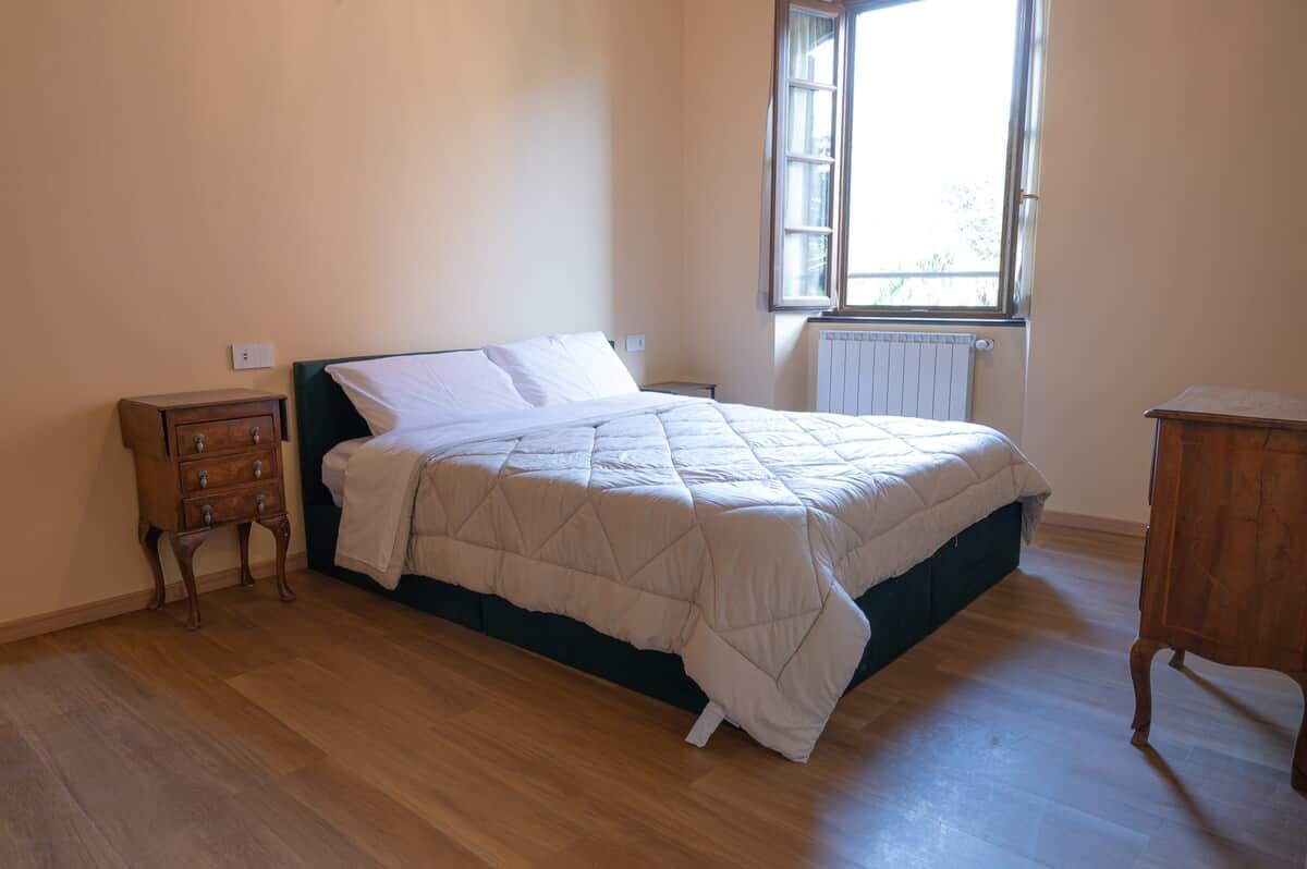 A bedroom with a bed, a nightstand, a dresser, and a window.