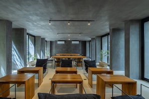 A modern conference room with a large table, chairs, and a high ceiling with exposed beams. - Ramada Residences by Wyndham Tulum (Tulum)