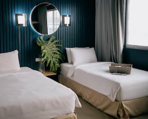Habitación de hotel con dos camas, un espejo grande, una planta en maceta y una ventana con cortinas.