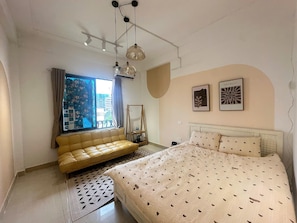 A bedroom with a bed, a sofa, a hanging light fixture, and two wall-mounted pictures. - Luxe Paradise Residence 21 Nguyen Van Troi (Hanoi)