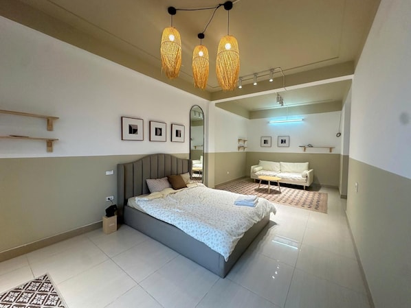 A modern bedroom with a large bed, bedside tables, a sofa, and a mirror. - Luxe Paradise Residence 21 Nguyen Van Troi (Hanoi)
